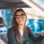 Happy brunette woman driving a car