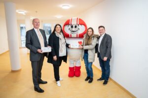 (C) David Bohmann / PID: Vizebürgermeisterin Kathrin Gaál (2.v.l.), Othmar Thann (l.) vom KFV und der Bezirksvorsteher von Meidling Wilfried (r.) Zankl übergeben gemeinsam mit dem Maskottchen Helmi (m.) einer frisch eingezogenen Mutter das Sicherheitskit für mehr Sicherheit in den eigenen 4 Wänden.