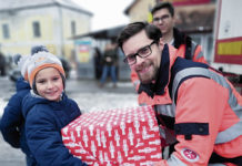 (C) Johanniter: Ein Johanniter-Helfer übergibt einem rumänischen Kind ein Packerl voll Lebensmittel.