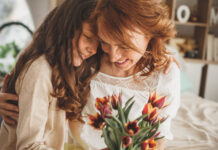 Kind schenkt Mutter Blumen zum Muttertag