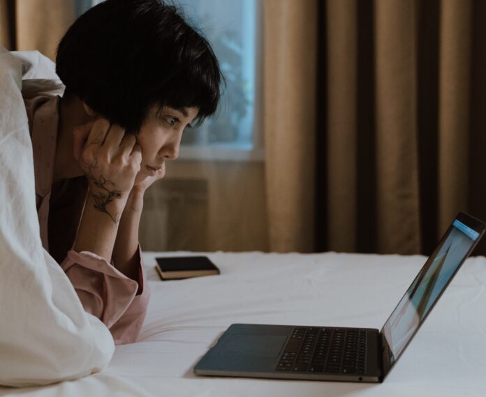 Eine Frau blickt auf den vor ihr stehenden Laptop.