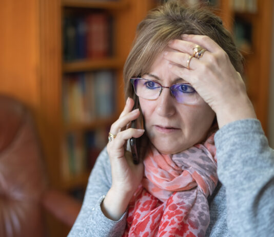 Frau telefoniert und macht besorgtes Gesicht