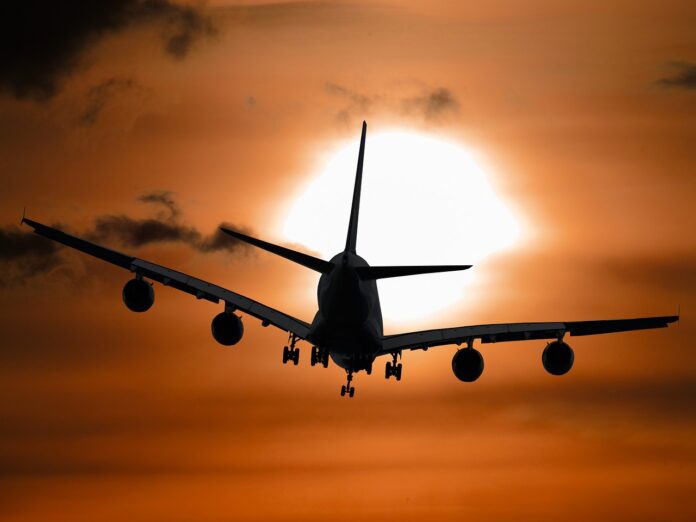 Ein Flugzeug fliegt in den Sonnenuntegang.