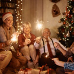 Happy multi-generation family using sparkles and having fun while celebrating Christmas at home.