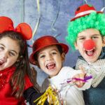 Three kids celebrating Carnival or New Years Eve