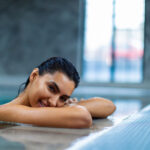 Beautiful young woman relaxing on indoors poolside