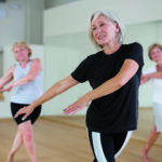 Senior women in sportswear dancing inside gym