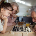 Close up of grandparents teaching a granddaughter how to play chess