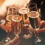 People clinking glasses with sparkling wine indoors , closeup