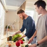 Young male gay couple preparing healthy vegetables for a meal in the kitchen