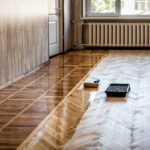 Lacquering wood floors. A roller to coating floors. Varnishing lacquering parquet floor by paint roller – second layer. Home renovation parquet