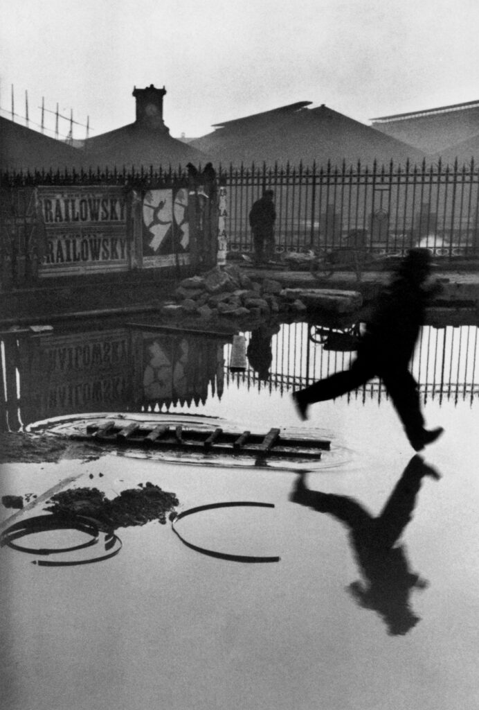 Ein Mann springt über eine Reenpfütze in Paris, Foto aus der Ausstelllung zu Henri Cartier-Bresson im Foto Asenal Wien 2025