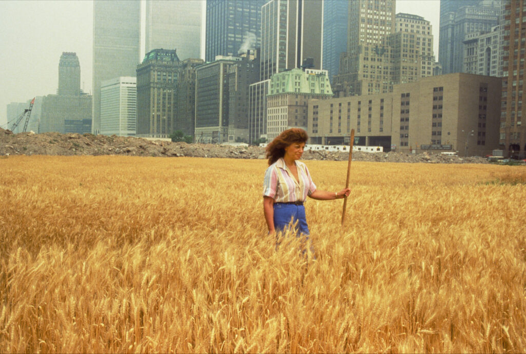 Ágnes Dénes, Wheatfield –A Confrontation: Battery Park Landfill, Downtown Manhattan – With Ágnes Dénes Standing in the Field (Weizen- feld – eine Konfrontation: Battery Park Lanfill, Downtown Manhattan – Mit Ágnes Dénes auf dem Feld), 1982, Fotografie von John McGrail, Chromogener Druck, 40 x 50cm © Ágnes Dénes Courtesy Leslie Tonkonow Artworks + Projects, New York 
